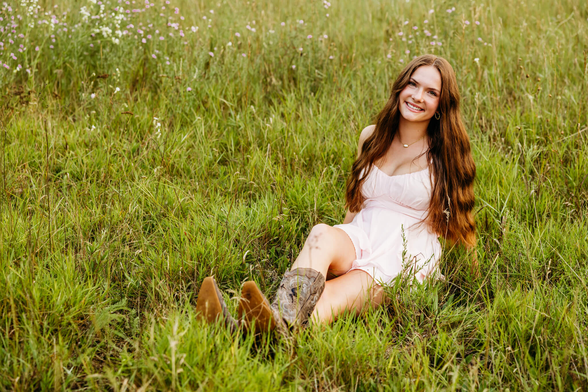Teenage girl in a romper and cowboy boots sitting in a flower field by Preble Park.