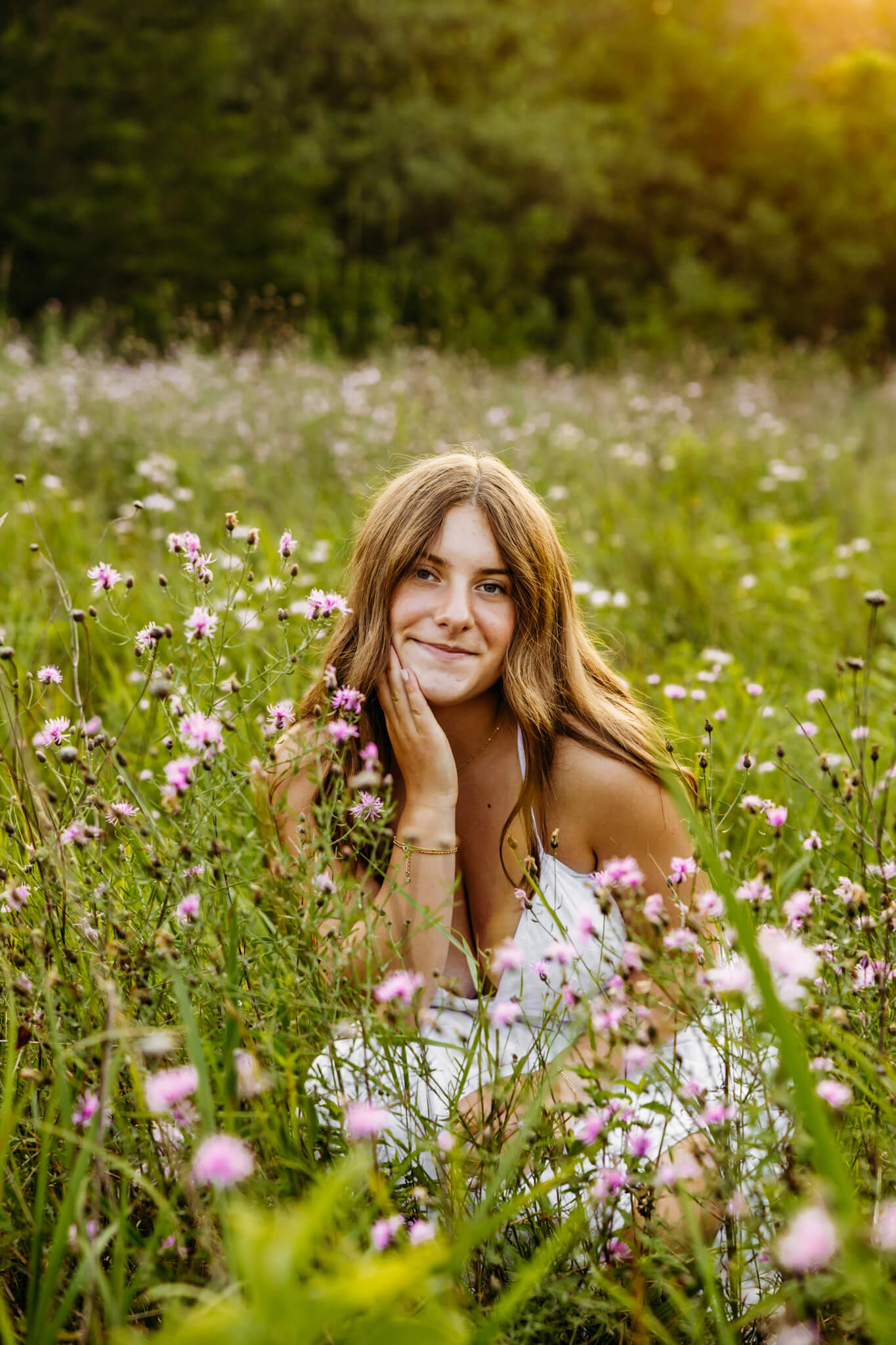 Little Chute High School senior girl sitting in a purple wildflower field at sunset for her photography session.