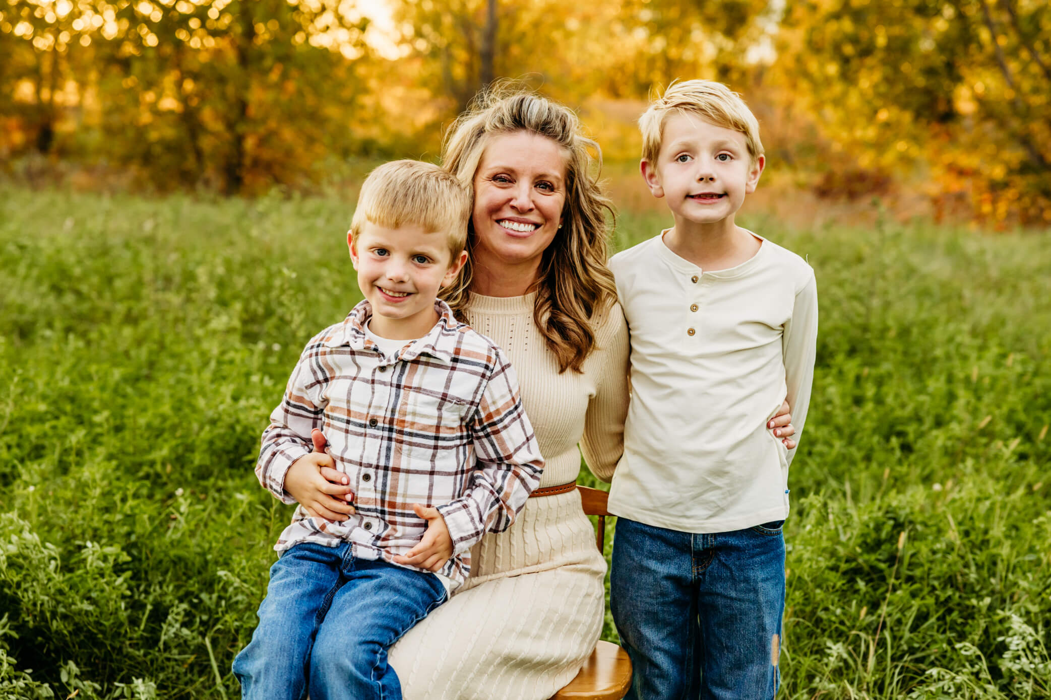 Mother sitting with her two sons in a fall field in Door County.